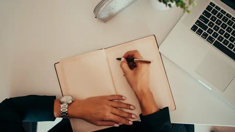 Person im Büro, die Notizen auf Papier schreibt