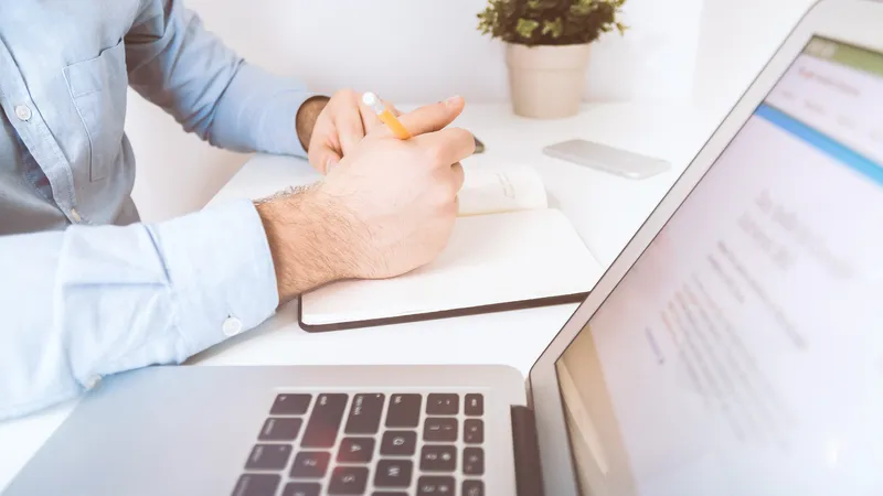 Person im Büro, die Notizen auf Papier schreibt