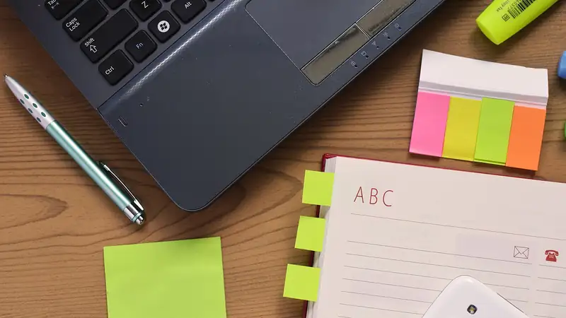 Schreibtisch mit Laptop, Notizblock und Stift