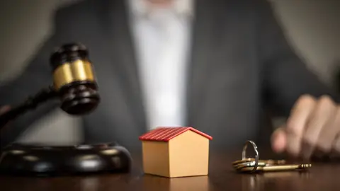 Hausmodell, Schlüssel und Richterhammer auf einem Tisch